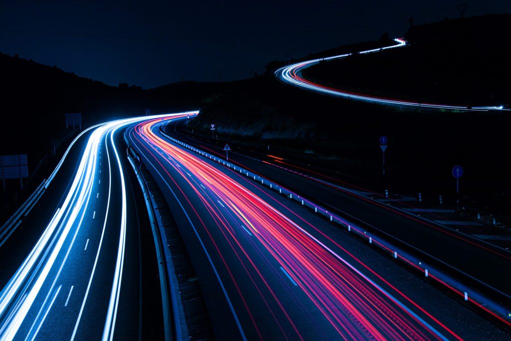 Pimeäkuva moottoritiestä, jossa autojen valot näkyvät pitkällä valotusajalla.