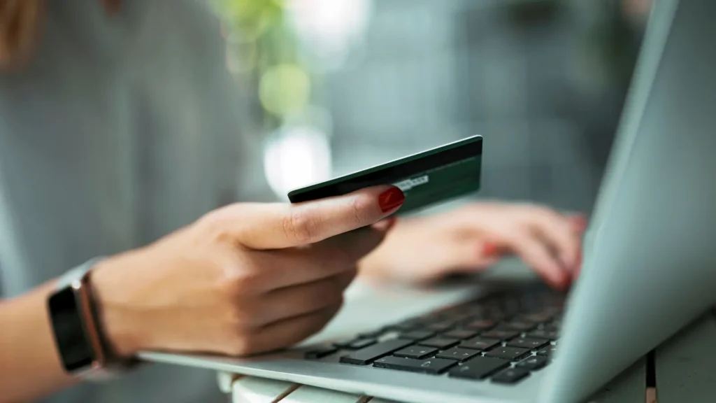 Nainen kirjoittamassa luottokorttitietoja tietokoneellaan