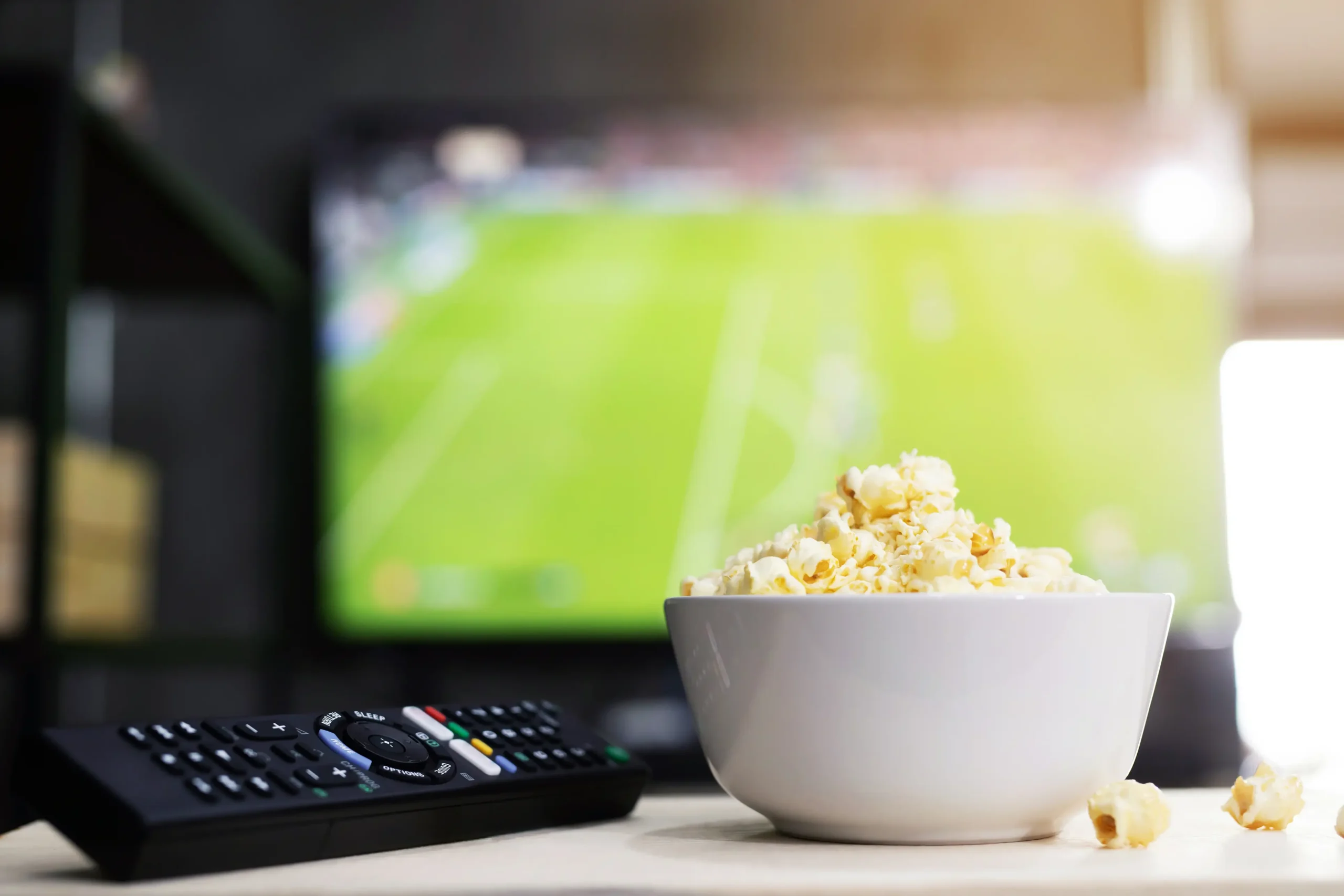 Kaukosäädin ja kulho popcornia tv:n edessä